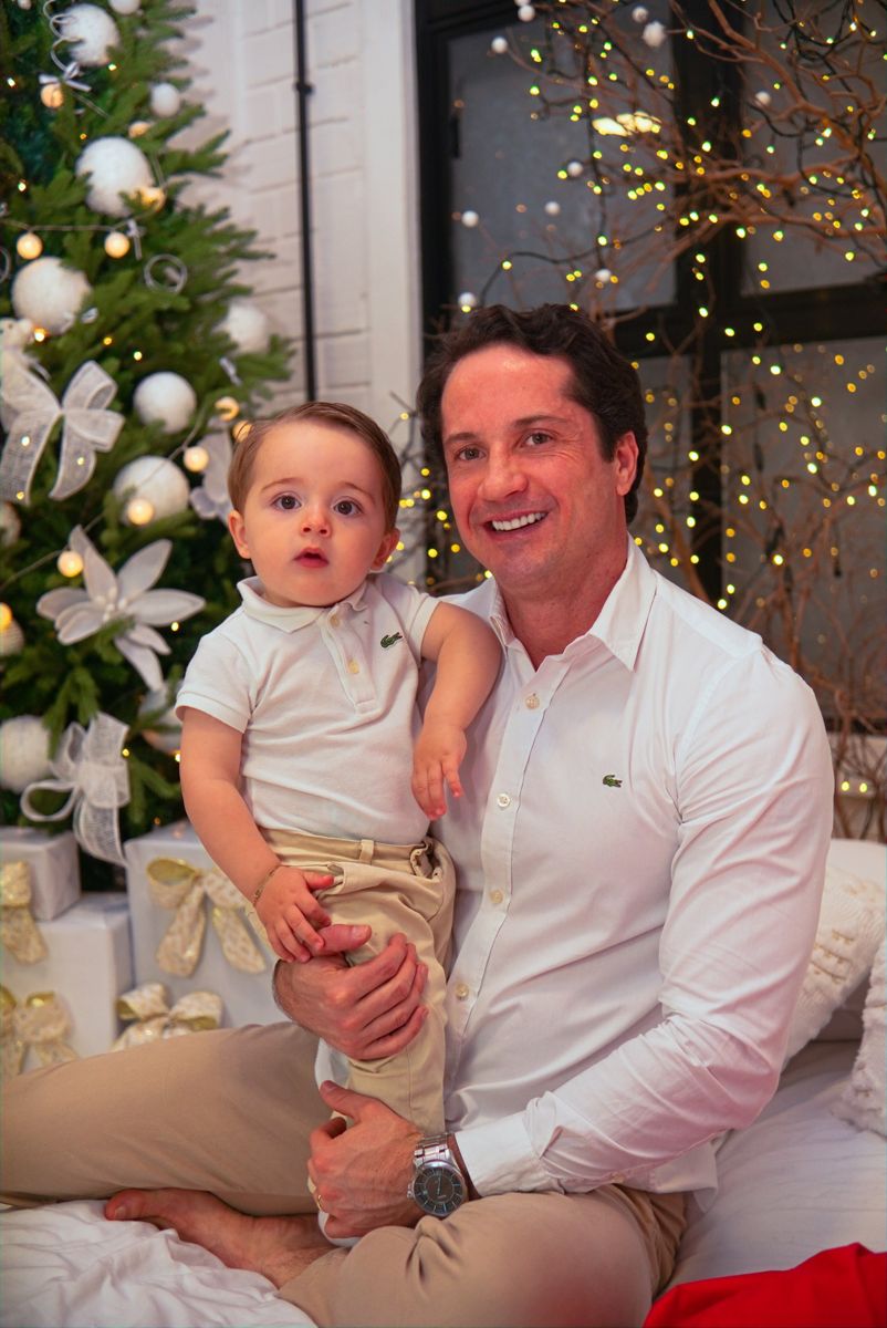Pai com o bebê ao lado da árvore de Natal